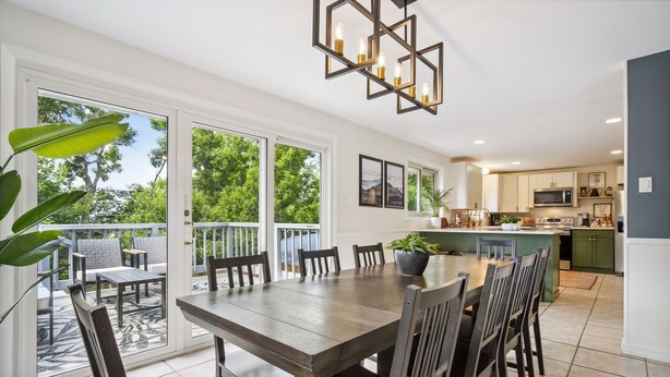 A modern kitchen with a central island, large windows, and a dining area with a wooden table and chairs. - Modern Huge Family Getaway | Fire Pit | 5BD/3BA (Arvada)