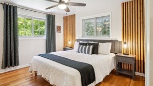 A bedroom with a bed, wooden panel walls, a ceiling fan, and a window with curtains. - Modern Huge Family Getaway | Fire Pit | 5BD/3BA (Arvada)