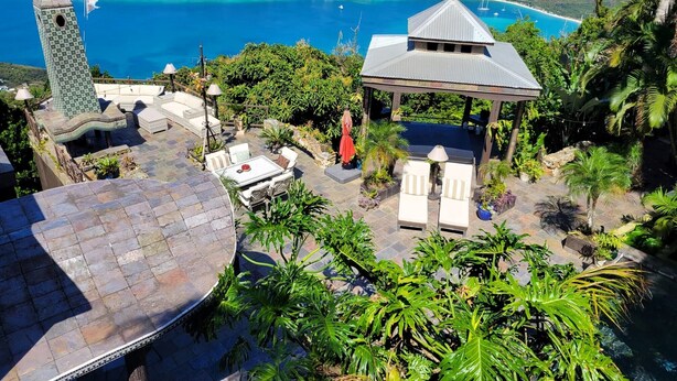 Um jardim no terraço com um gazebo, cadeiras de descanso e vista para o mar.