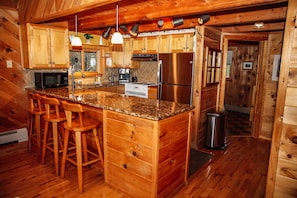 Fully equipped kitchen with a central island and bar stools, featuring a refrigerator, microwave, and stove.