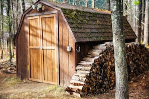 Rustic shed with a central door and adjacent firewood storage.