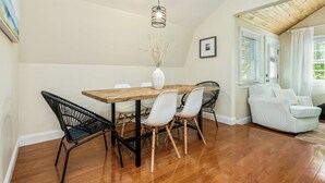A dining area with a wooden table, white chairs, a black chair with a woven backrest, and a white vase with branches. - The Nest-Cozy Retreat Near Portsmouth +Ogunquit, Full kitchen, close to every... (York)