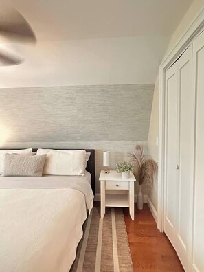 A bedroom with a bed, bedside table, lamp, and a wardrobe.