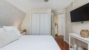 A bedroom with a large bed, a TV mounted on the wall, and a hallway leading to another room. - The Nest-Cozy Retreat Near Portsmouth +Ogunquit, Full kitchen, close to every... (York)