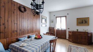 Ein Essbereich mit karierter Tischdecke, Holzwandverkleidung, einer Kristallleuchtre und einem Holzschrank.