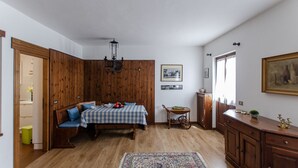 Ein Zimmer mit einer holzverkleideten Wand, einem mit kariertem Tuch bedeckten Esstisch, einem gemusterten Teppich und einer Vitrine mit Dekorationen.