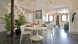 Een moderne woonkamer met een ronde eettafel, witte stoelen en een trap met een witte leuning.