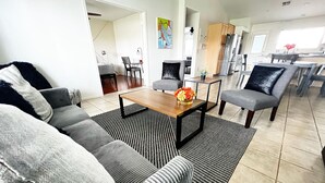 Ein modernes Wohnzimmer mit einer Couch, einem Couchtisch und einem Essbereich mit Stühlen.
