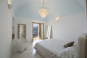 Un dormitorio con cama, una silla, una araña y vistas al exterior.
