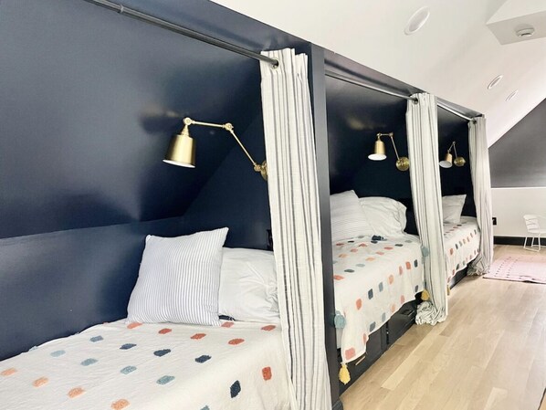 Une chambre à coucher avec deux lits, chacun doté d’un baldaquin, de draps blancs et d’un motif à pois.