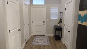 Un couloir avec trois portes blanches, une petite table sur laquelle est posé un vase, et un tapis à motifs.