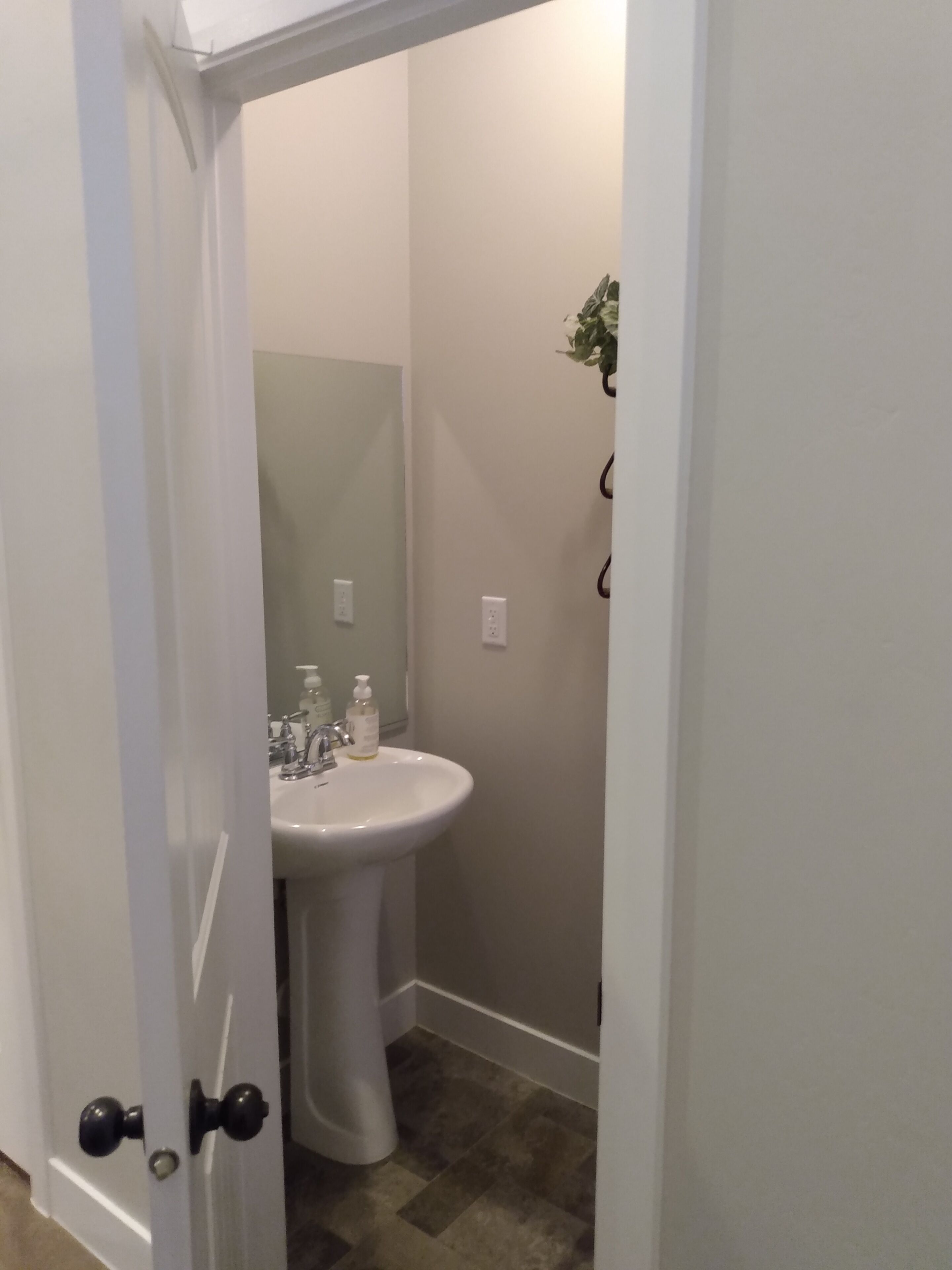 A bathroom with a white sink, a mirror, and a door with a black handle.