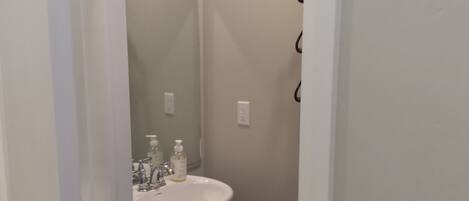 A bathroom with a white sink, a mirror, and a door with a black handle.