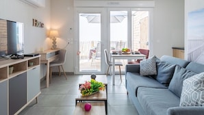 Ett modernt vardagsrum med en soffa, en tv och en matplats med ett bord och stolar.