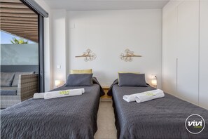 A hotel room with two beds, a sofa, and a large window.