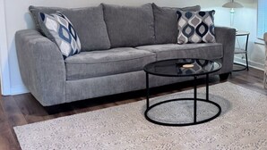 A grey sofa with patterned cushions, a round glass coffee table, and a speckled rug in a living room. - Comfortable Open Space. Pets are allowed (Beaufort)