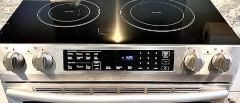 A stainless steel stove with four burners and a digital control panel.