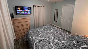 A bedroom with a bed, a dresser, a TV on the wall, a ceiling fan, and a door. - Comfortable Open Space. Pets are allowed (Beaufort)