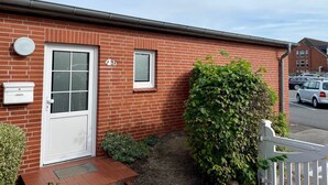 A red brick house with a white door, a small window, and a mailbox. - Adrian 5 - Simple, central apartment for 2 persons, incl. WLAN and TV, separate (Sylt)