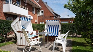 An outdoor patio with a table and two chairs, one with a blue and white striped cushion. - Adrian 5 - Simple, central apartment for 2 persons, incl. WLAN and TV, separate (Sylt)