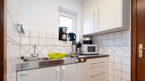 A compact kitchen with white cabinets, a sink, a coffee maker, and a microwave. - Adrian 5 - Simple, central apartment for 2 persons, incl. WLAN and TV, separate (Sylt)