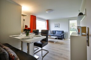 Un salon moderne comprenant un coin repas, un canapé, une table basse et un réfrigérateur.