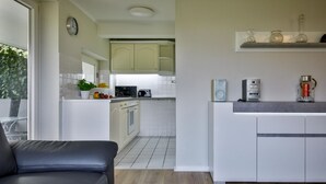 Una cocina moderna con armarios blancos, microondas y cafetera sobre la encimera.