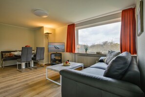 Un salon moderne comprenant un canapé, une table basse, un téléviseur et un coin repas.