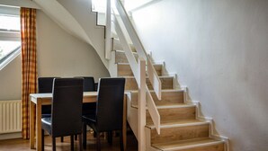 Una escalera de madera con barandillas blancas que conduce a un cuarto con una mesa y sillas para comer.
