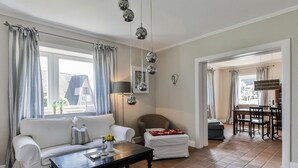 A living room with a sofa, a coffee table, and a dining area with chairs and a table. - Lena's Hüs - Beautiful thatched house for 6 pers. with sea view, garden, WLAN, (List)