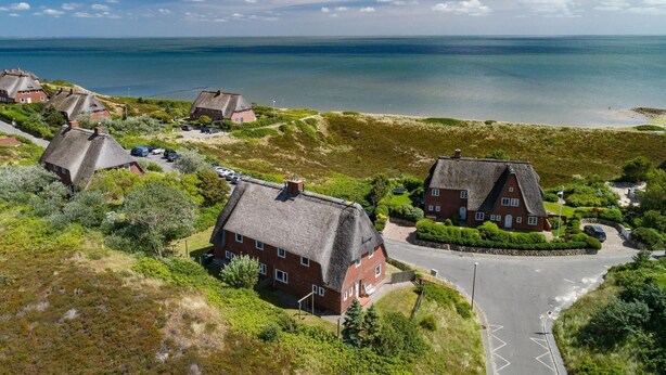 A coastal village with traditional thatched-roof houses, a road, and a view of the sea. - Lena's Hüs - Beautiful thatched house for 6 pers. with sea view, garden, WLAN, (List)