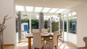 Un comedor con mesa y sillas, ventanas amplias y vistas al exterior.