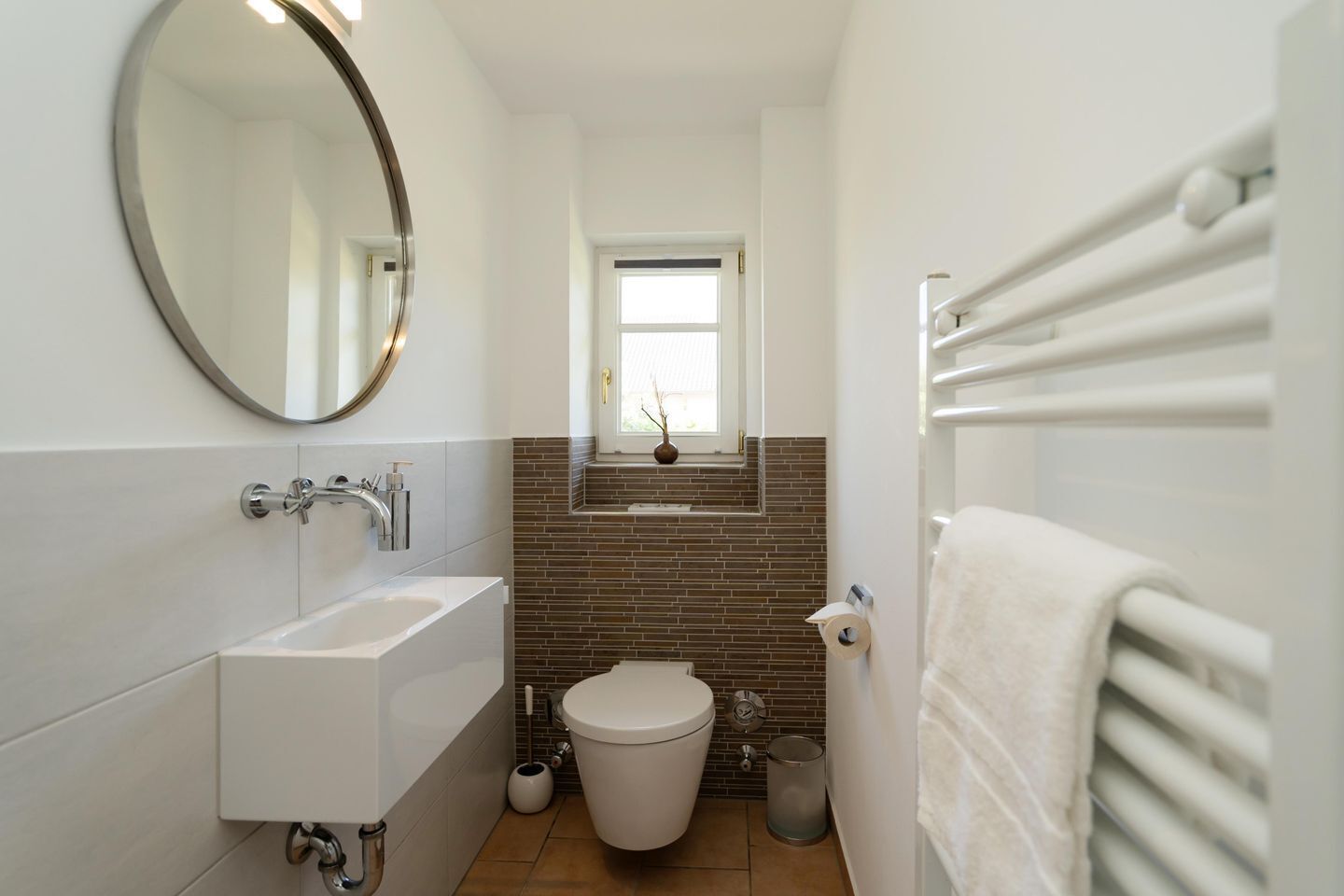 A modern bathroom with a white sink, a toilet, and a mirror.