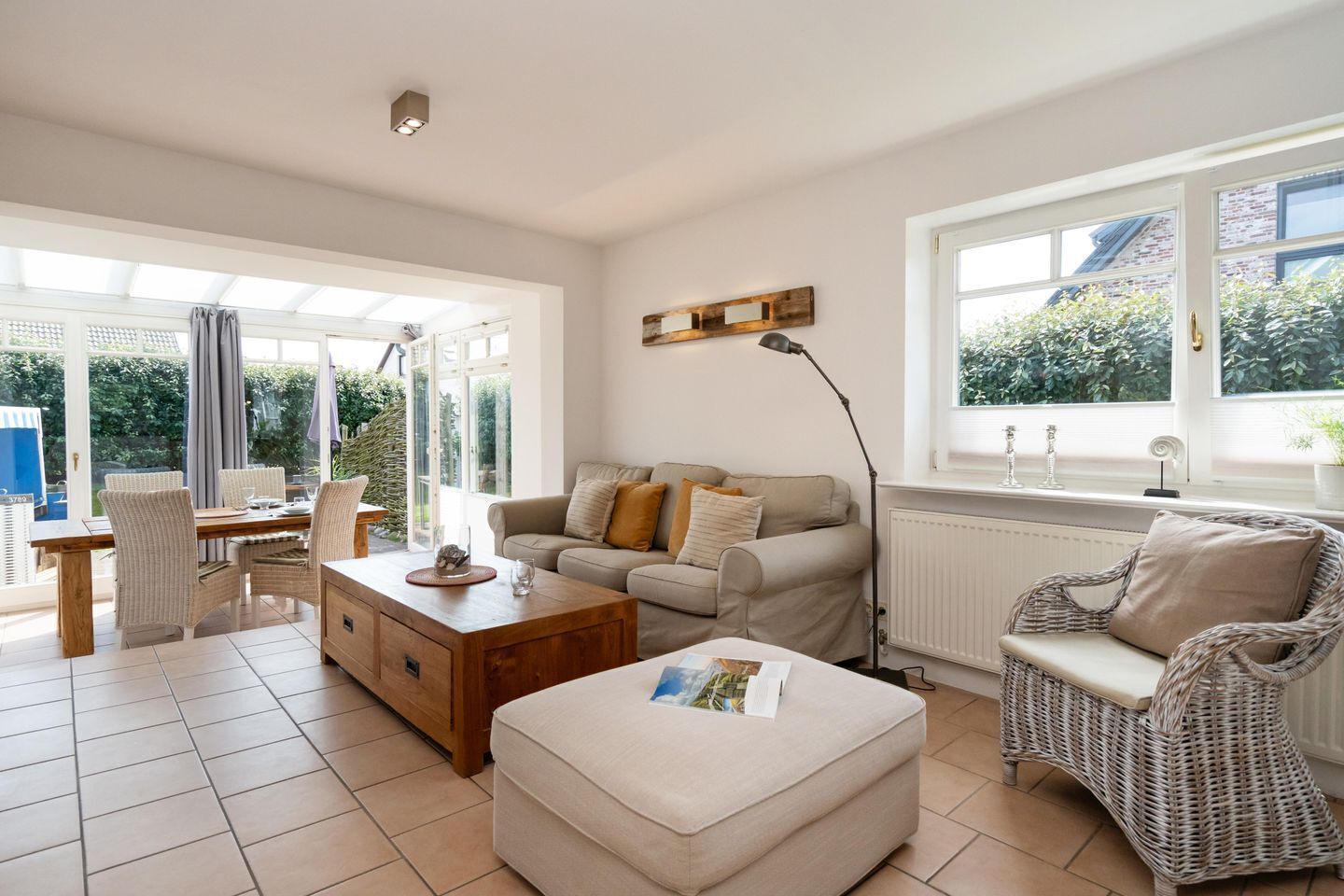 A well-lit living room with a sofa, a coffee table, and a dining area with chairs and a table.