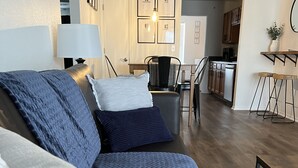 Ein modernes Wohnzimmer mit einer Couch, einem Essbereich und einer Küche im Hintergrund.