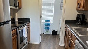 Eine moderne Küche mit Holzschränken, Edelstahlgeräten und einer schwarzen Arbeitsplatte.