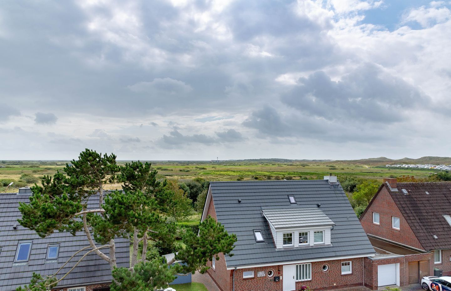 Et boligområde med huse, en klar himmel og et fjerntliggende marklandskab.