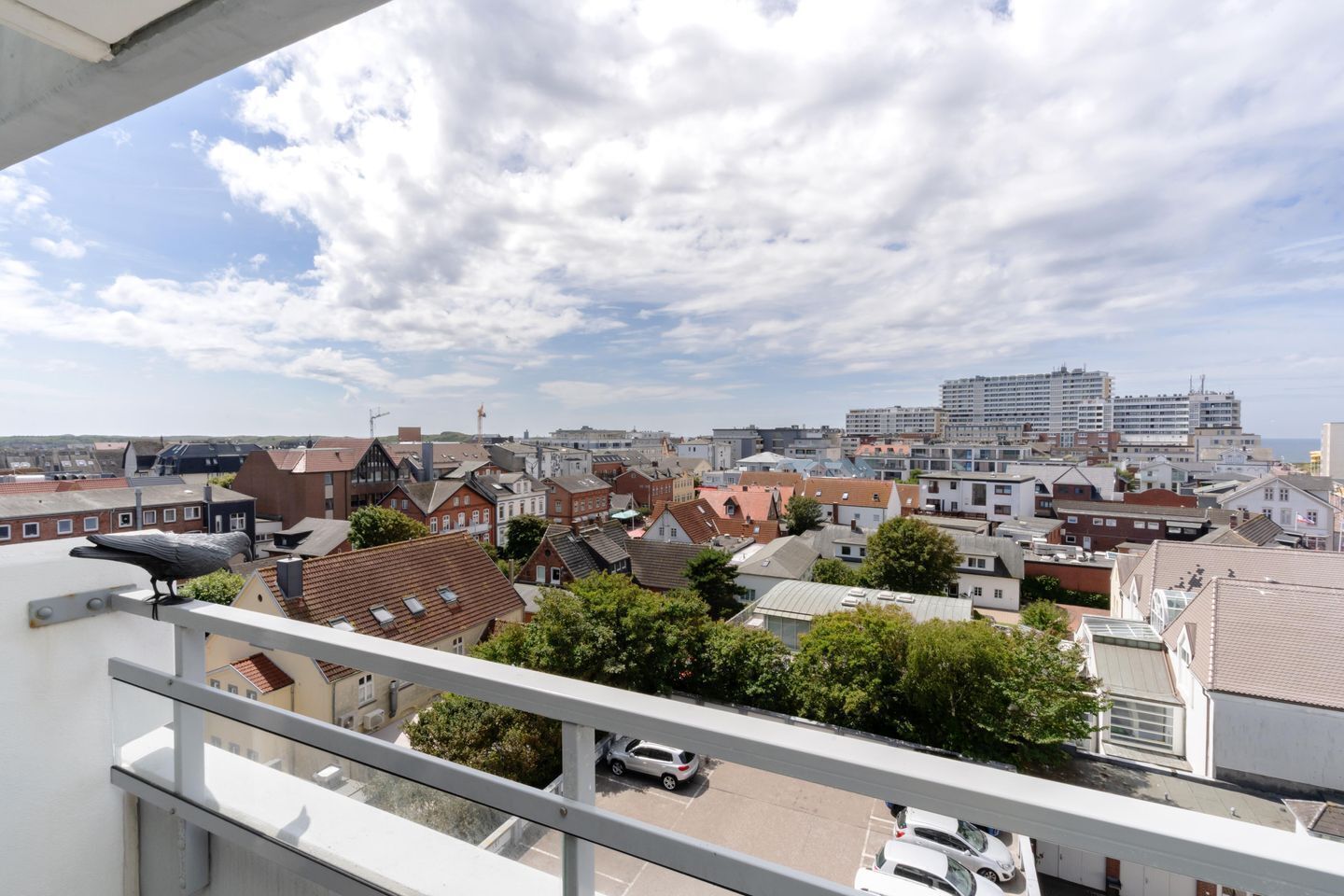 Ein Wohngebiet mit einer Mischung aus traditionellen und modernen Gebäuden, einem klaren Himmel und einem Vogel auf einem Balkon.