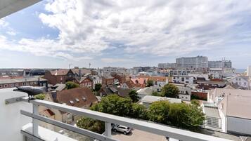 Ein Wohngebiet mit einer Mischung aus traditionellen und modernen Gebäuden, einem klaren Himmel und einem Vogel auf einem Balkon.