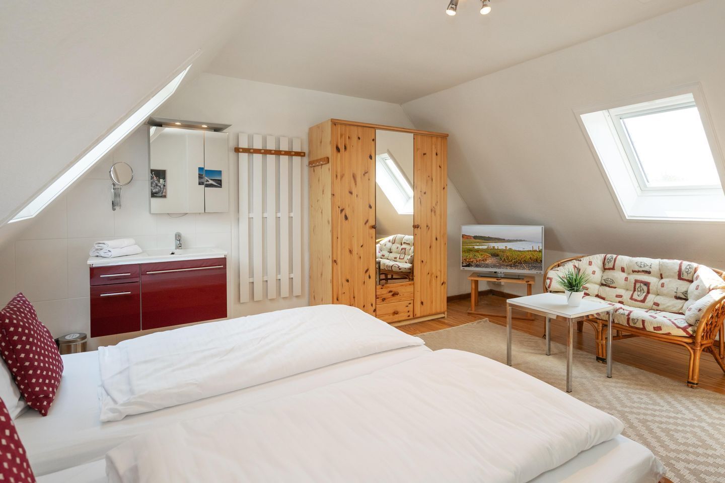 A bedroom with a bed, a wardrobe, a TV, a sofa, and a window.
