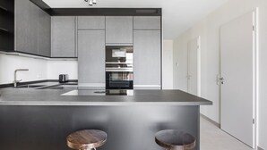 Una cocina moderna con una isla central, taburetes de bar, horno empotrado y un diseño elegante.