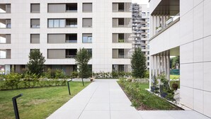 Un edificio moderno con un patio central, que incluye un sendero, vegetación y una fuente de agua.
