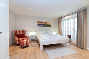 Una habitación de hotel moderna con una cama, una silla, una mesita de noche y un cuadro en la pared.