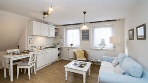 Un espacio habitable compacto con kitchenette, comedor, sofá y ventana con cortinas.