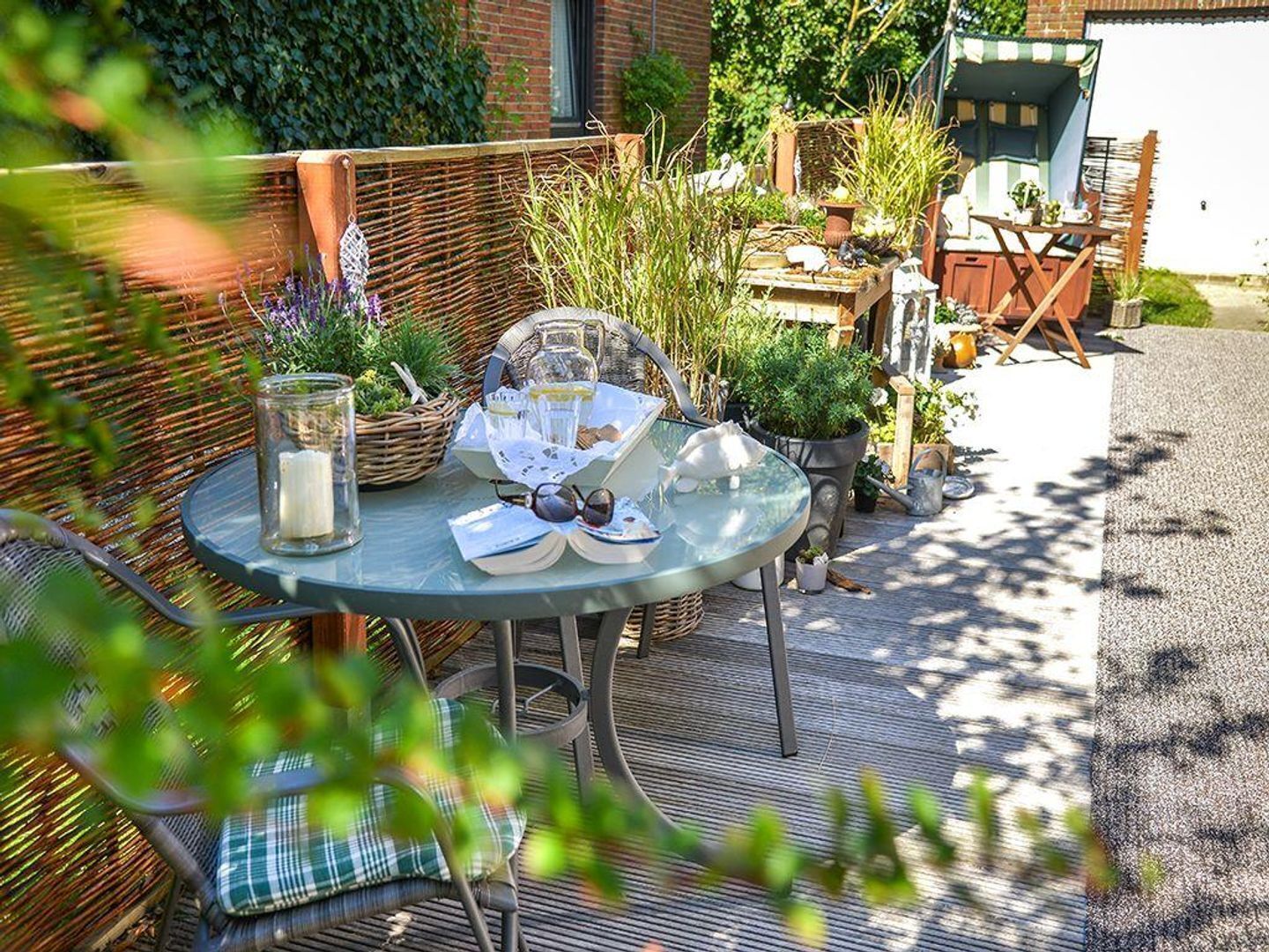 A round glass table with a wicker chair, a basket, and a glass jar.