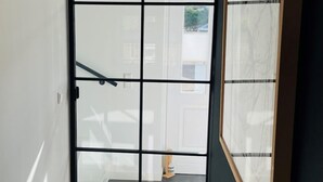 A room with a sliding glass door leading to a balcony, a framed artwork on the wall, and a wooden floor.
