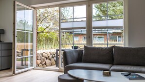 A modern living room with a gray sofa, a round coffee table, and a sliding glass door leading to a patio area.
