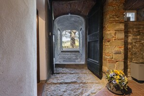 A stone corridor leading to a staircase, with a view of a tree and landscape. - Villa Leone by MMega (Capannori)