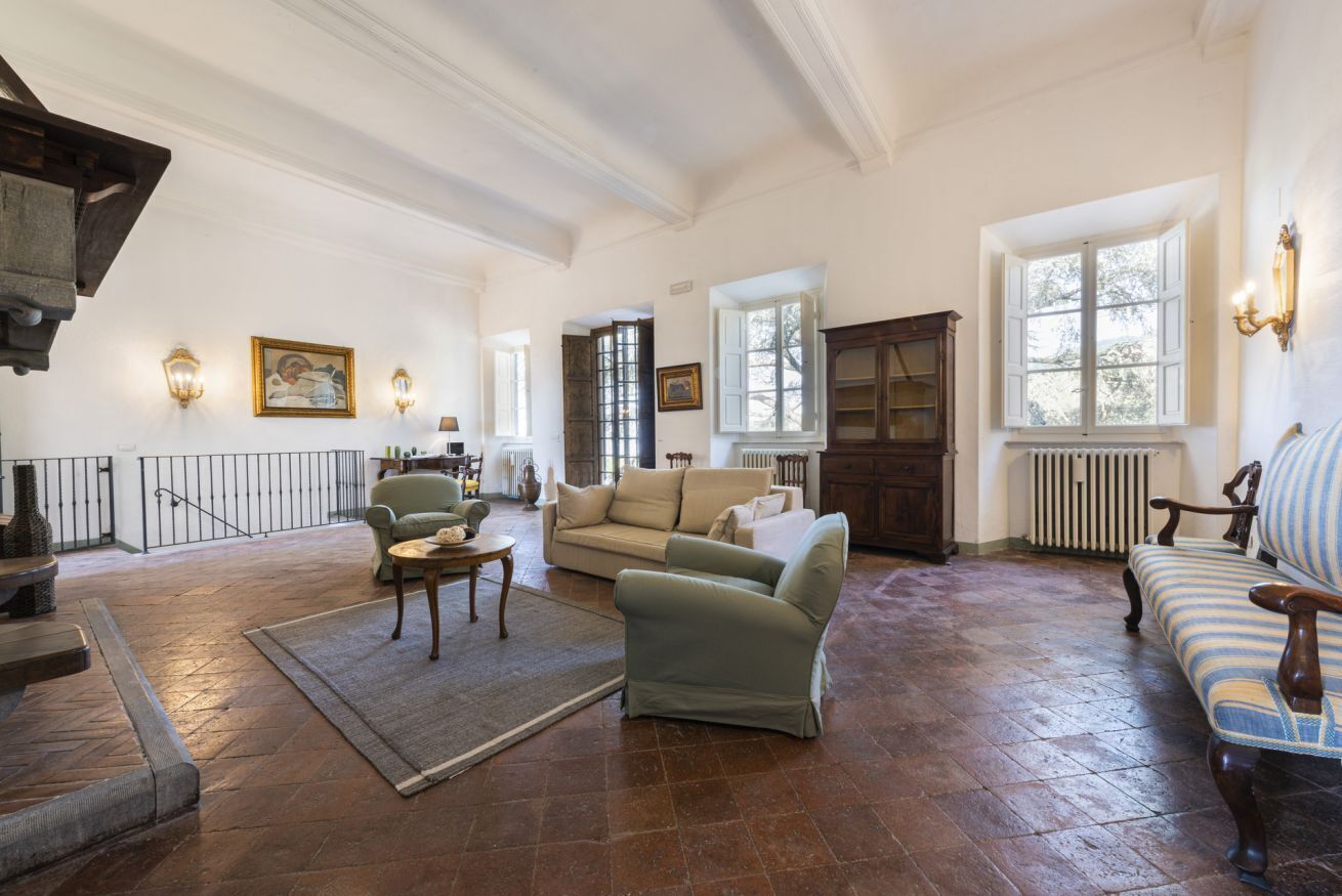 A spacious living room with a fireplace, a sofa, a coffee table, and a patterned rug.