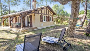 A rustic cabin with a porch, two lawn chairs, and a table. - Villa de la Côte - Welkeys (Labenne)
